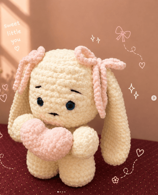 Handmade cream crochet bunny with pink ribbon ears, holding a pink crochet heart